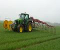 Traktor se pohybuje v porostu vzrostlého obilí